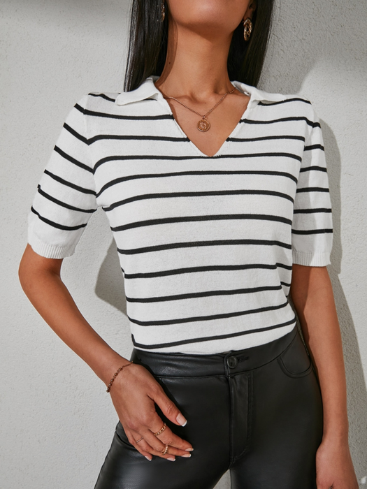 Woman wearing a black and white striped V-neck top with short sleeves and contrast collar, styled with jeans for a chic everyday look.