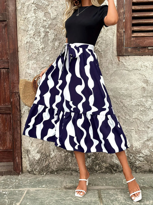 Woman wearing printed round neck short sleeve midi dress with tied waist in a casual outdoor setting
