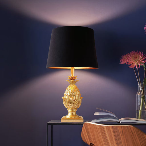 Pineapple table lamp with gold resin base and black satin drum shade with gold lining
