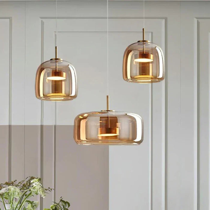 Nordic-style smoky gray and amber glass pendant light hanging over a modern dining table with soft warm lighting

