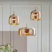 Nordic-style smoky gray and amber glass pendant light hanging over a modern dining table with soft warm lighting

