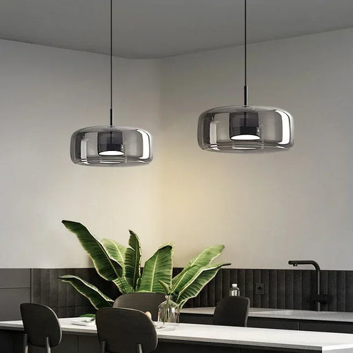 Nordic-style smoky gray and amber glass pendant light hanging over a modern dining table with soft warm lighting