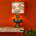  table lamp with bulbous resin base and patterned linen and black fabric shade on side table

