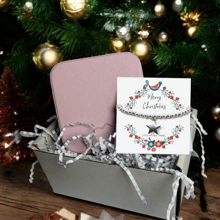Small Christmas gift hamper containing a silver star charm stretch beaded bracelet on a message card and a pink square PU leather travel jewellery box.
