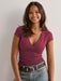 Model wearing a flattering basic top with crossover neckline and soft stretch fabric in a casual setting