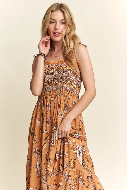Woman wearing a smocked printed square neck cami dress with tie shoulders in a sunny outdoor setting