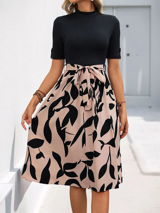 Woman wearing printed mock neck short sleeve dress with tie detail