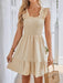 Woman wearing a ruched, ruffled smocked dress with a fitted bodice and flared hem