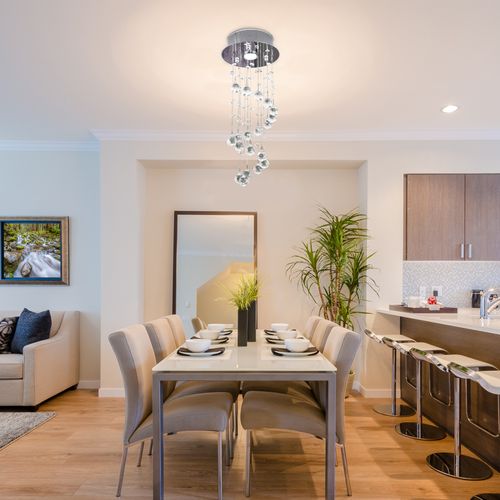 Modern crystal spiral chandelier with chrome finish and K9 glass droplets hanging in a hallway setting.

