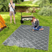 Reversible waterproof outdoor rug with carry bag laid out in a garden setting