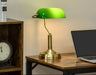 Classic banker’s desk lamp with antique bronze base and green glass shade on wooden desk
